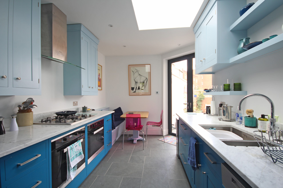 Zweizeilige, Mittelgroße Moderne Wohnküche mit Doppelwaschbecken, Schrankfronten mit vertiefter Füllung, blauen Schränken, Marmor-Arbeitsplatte, Küchengeräten aus Edelstahl, grauem Boden und grauer Arbeitsplatte in Sonstige