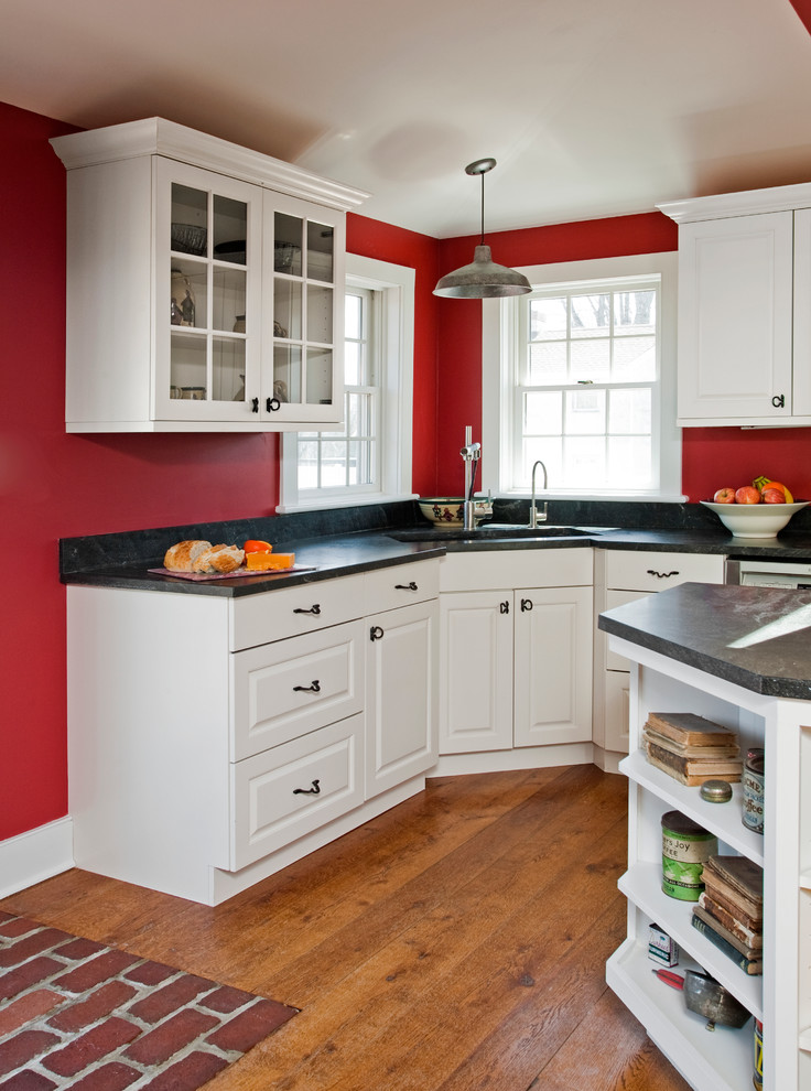 Bild på ett stort lantligt kök, med en undermonterad diskho, luckor med upphöjd panel, vita skåp, granitbänkskiva, grått stänkskydd, stänkskydd i sten, rostfria vitvaror, mörkt trägolv och en köksö