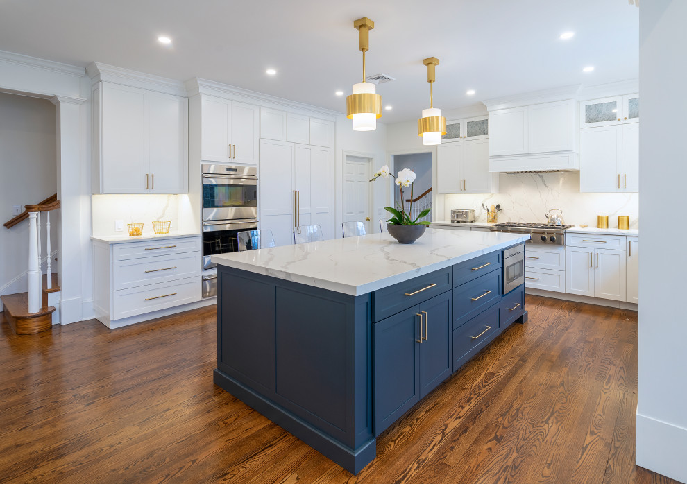 Photo of a large traditional kitchen in Philadelphia with a submerged sink, shaker cabinets, white cabinets, engineered stone countertops, white splashback, engineered quartz splashback, stainless steel appliances, dark hardwood flooring, an island, brown floors and white worktops.