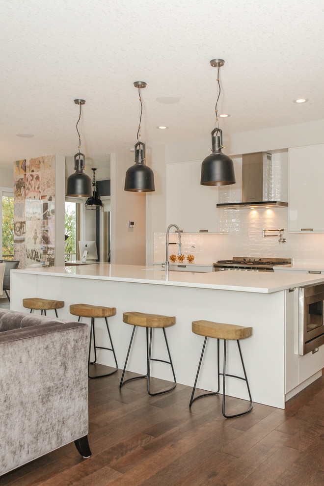 Offene Moderne Küche mit Landhausspüle, flächenbündigen Schrankfronten, weißen Schränken, Küchenrückwand in Weiß, braunem Holzboden und Kücheninsel in Edmonton