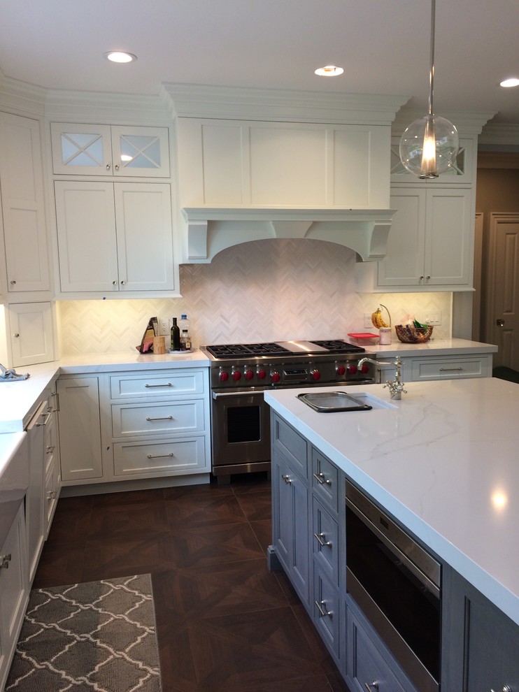 Inspiration for a large classic l-shaped kitchen/diner in New York with a belfast sink, beaded cabinets, white cabinets, engineered stone countertops, white splashback, marble splashback, stainless steel appliances, porcelain flooring, an island and brown floors.