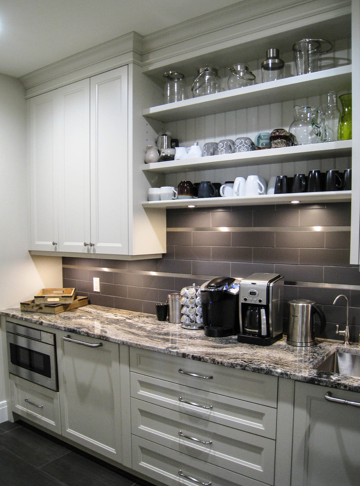 Immagine di una cucina tradizionale con lavello sottopiano, ante beige, top in granito, paraspruzzi grigio, elettrodomestici in acciaio inossidabile e pavimento grigio