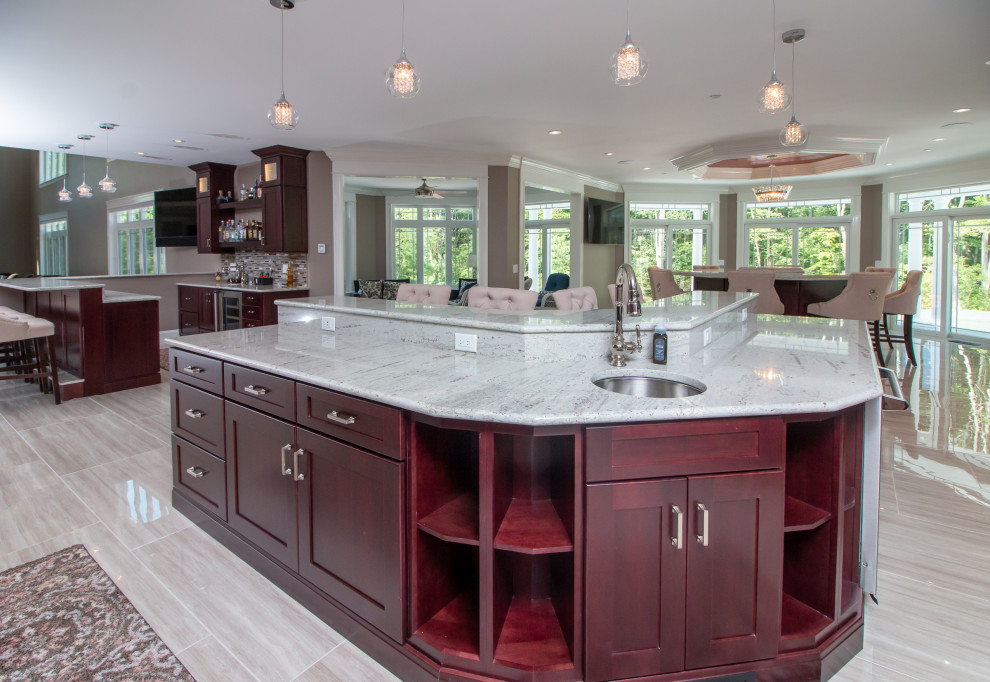 Huge transitional l-shaped porcelain tile and beige floor eat-in kitchen photo in Boston with a farmhouse sink, recessed-panel cabinets, medium tone wood cabinets, granite countertops, multicolored backsplash, glass tile backsplash, stainless steel appliances, an island and multicolored countertops