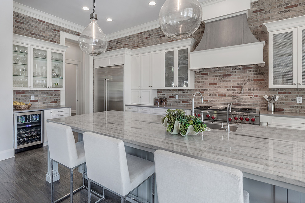 Inspiration for a large classic l-shaped open plan kitchen in Tampa with a belfast sink, shaker cabinets, white cabinets, quartz worktops, red splashback, brick splashback, stainless steel appliances, dark hardwood flooring, an island and brown floors.