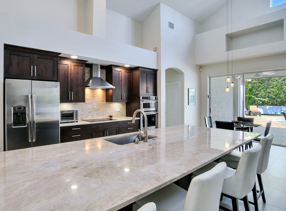Photo of a medium sized classic l-shaped kitchen/diner in Tampa with shaker cabinets, brown cabinets, quartz worktops, stainless steel appliances and an island.