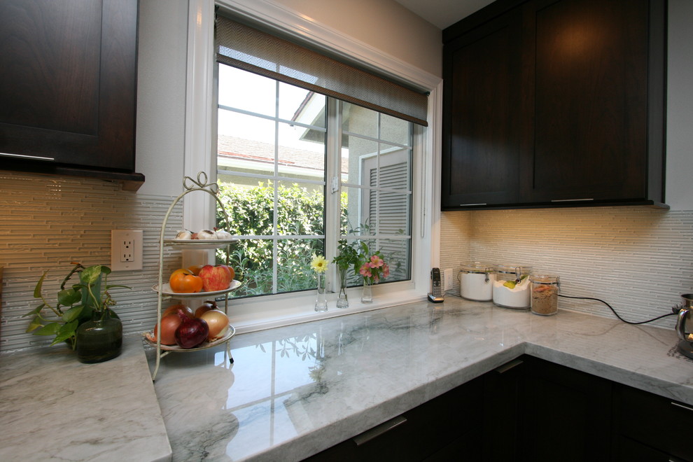 Exempel på ett mellanstort klassiskt l-kök, med en dubbel diskho, luckor med infälld panel, skåp i mörkt trä, bänkskiva i kvartsit, vitt stänkskydd, stänkskydd i glaskakel, rostfria vitvaror och klinkergolv i porslin