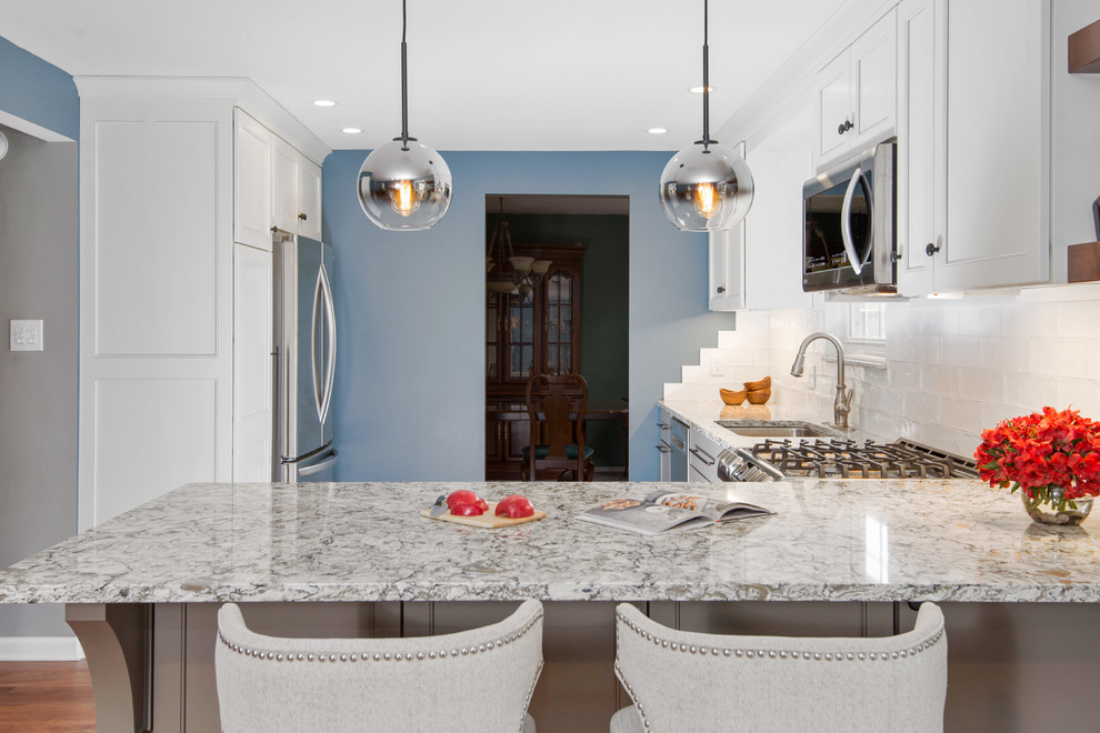 Transitional l-shaped vinyl floor and brown floor eat-in kitchen photo with an undermount sink, beaded inset cabinets, white cabinets, quartz countertops, white backsplash, ceramic backsplash, stainless steel appliances and multicolored countertops