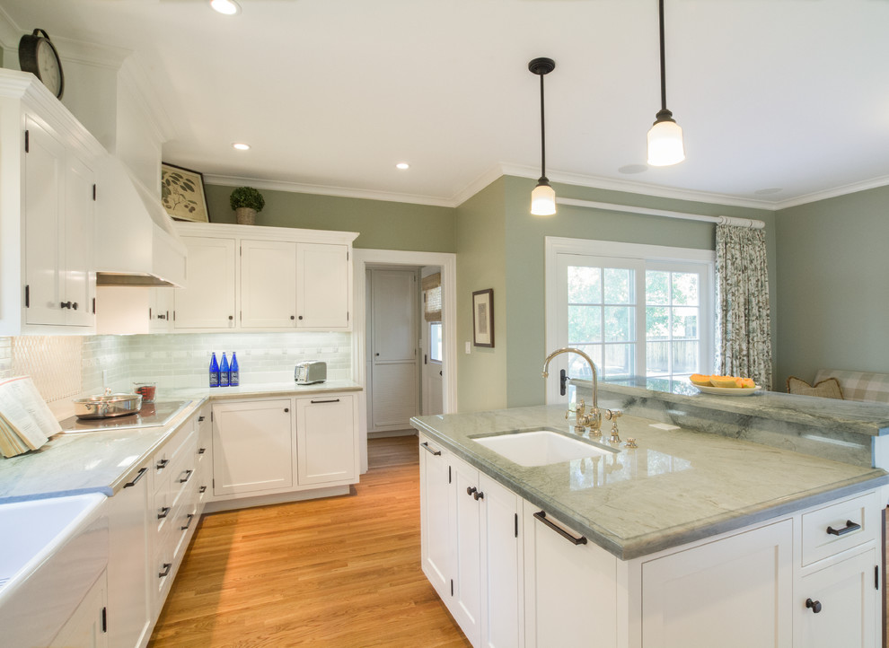 Example of a large classic l-shaped medium tone wood floor open concept kitchen design in Los Angeles with an island, shaker cabinets, white cabinets, quartz countertops, green backsplash, ceramic backsplash, stainless steel appliances and a farmhouse sink