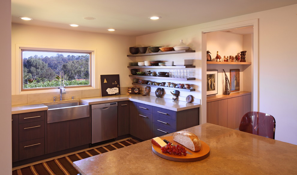 Eat-in kitchen - mediterranean eat-in kitchen idea in Los Angeles with a farmhouse sink, stainless steel appliances, flat-panel cabinets, dark wood cabinets, beige backsplash and no island