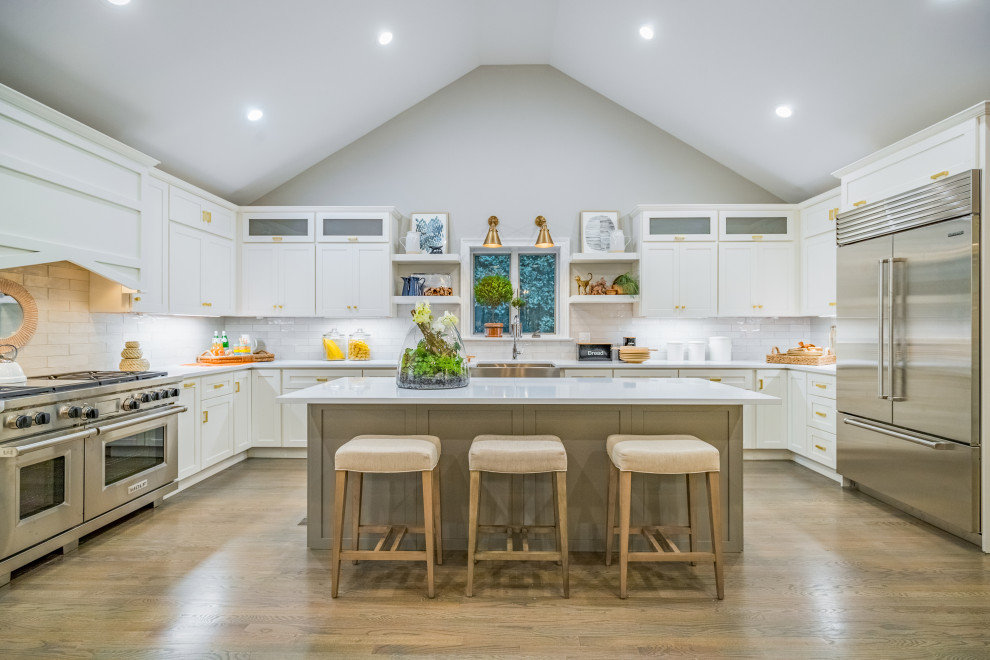 Immagine di una grande cucina country con lavello stile country, ante con riquadro incassato, ante bianche, paraspruzzi bianco, paraspruzzi con piastrelle diamantate, elettrodomestici in acciaio inossidabile, parquet chiaro, pavimento beige e top bianco