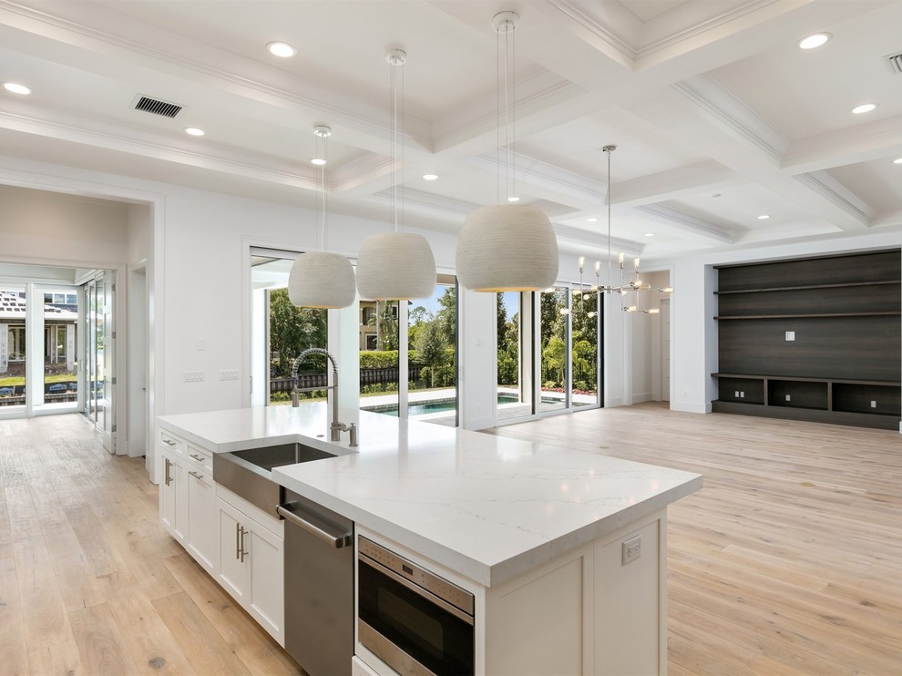This is an example of a large traditional l-shaped open plan kitchen in Orlando with a belfast sink, shaker cabinets, white cabinets, quartz worktops, white splashback, metro tiled splashback, stainless steel appliances, medium hardwood flooring, an island, brown floors and white worktops.