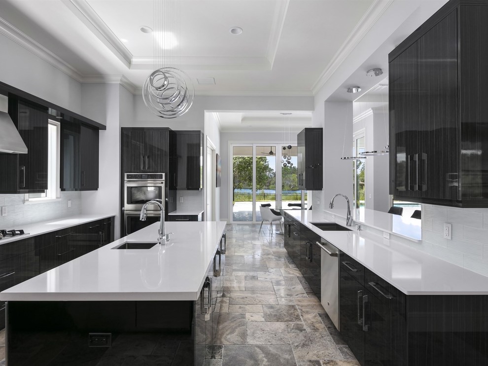 Foto di una grande cucina minimalista chiusa con lavello sottopiano, ante lisce, ante nere, top in superficie solida, paraspruzzi bianco, paraspruzzi con piastrelle di vetro, elettrodomestici in acciaio inossidabile, pavimento in travertino e pavimento grigio