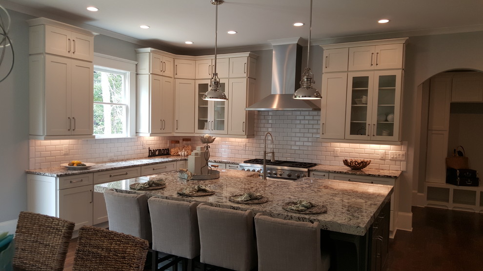 This is an example of a large classic u-shaped kitchen/diner in Atlanta with a belfast sink, shaker cabinets, white cabinets, granite worktops, white splashback, ceramic splashback, stainless steel appliances, dark hardwood flooring and an island.