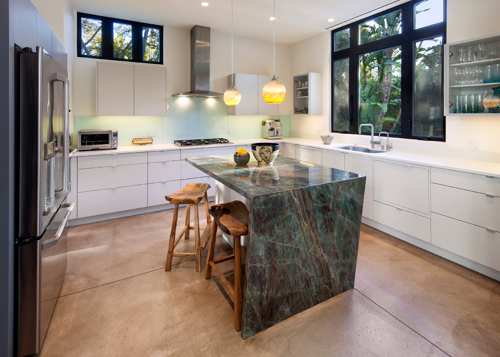 Inspiration for a mid-sized mediterranean u-shaped concrete floor kitchen remodel in Santa Barbara with a double-bowl sink, flat-panel cabinets, white cabinets, granite countertops, white backsplash, glass sheet backsplash, stainless steel appliances and an island