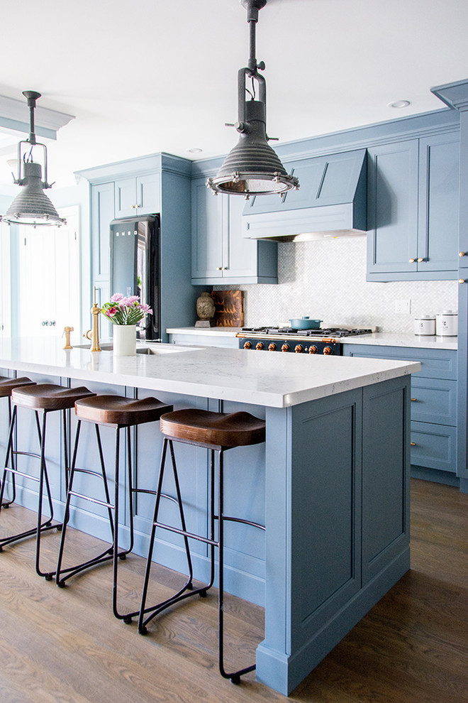 Idee per una cucina chic di medie dimensioni con lavello da incasso, ante blu, paraspruzzi bianco, elettrodomestici neri, pavimento marrone e top bianco