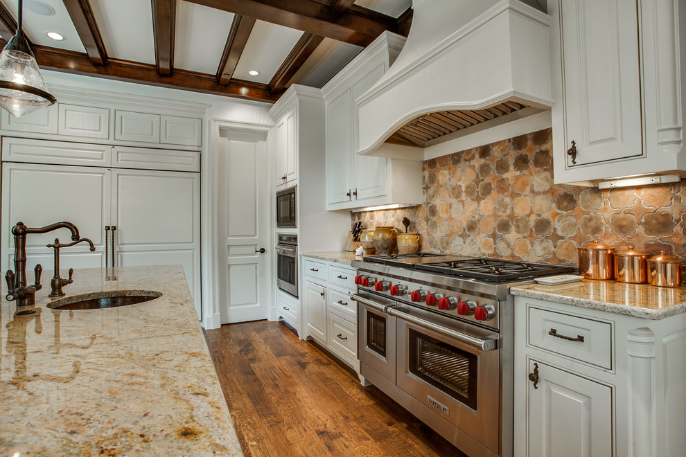 Inspiration for a traditional galley kitchen/diner in Dallas with a double-bowl sink, raised-panel cabinets, white cabinets, beige splashback, stainless steel appliances and medium hardwood flooring.