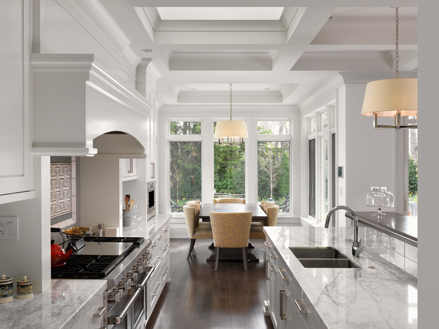 Inspiration for a timeless galley dark wood floor and brown floor kitchen remodel in Other with an undermount sink, shaker cabinets, white cabinets, marble countertops, white backsplash, ceramic backsplash, paneled appliances, an island and white countertops