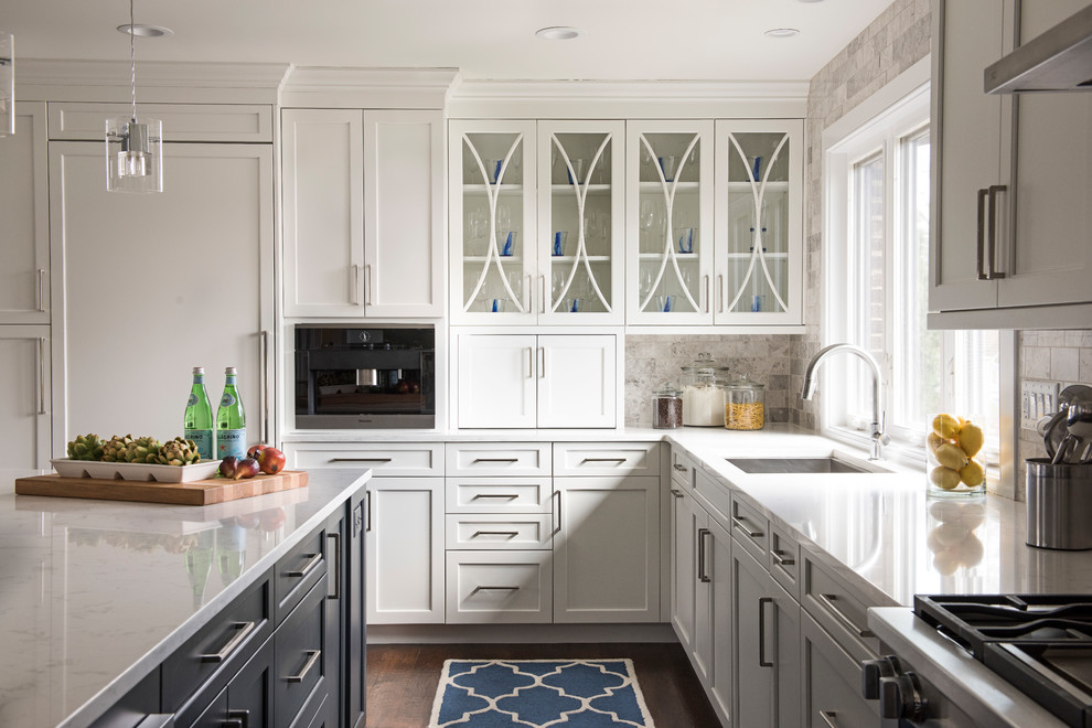Photo of a large traditional l-shaped kitchen/diner in Philadelphia with white cabinets, engineered stone countertops, grey splashback, stainless steel appliances, dark hardwood flooring, an island, a submerged sink, shaker cabinets, stone tiled splashback and brown floors.
