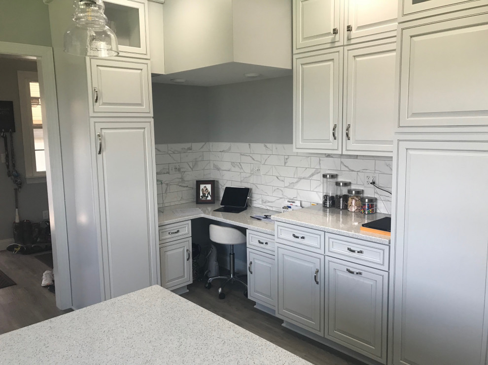 This is an example of a large rural u-shaped kitchen/diner in Chicago with a belfast sink, raised-panel cabinets, white cabinets, engineered stone countertops, grey splashback, porcelain splashback, stainless steel appliances, vinyl flooring, an island, grey floors and white worktops.