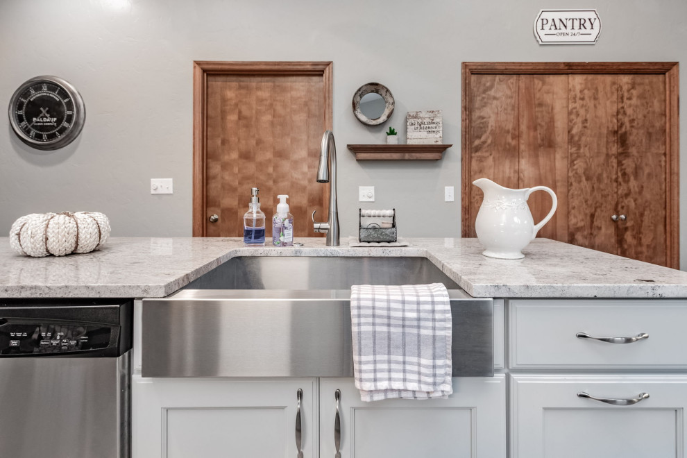 Bild på ett mellanstort lantligt u-kök, med en rustik diskho, skåp i shakerstil, grå skåp, granitbänkskiva, vitt stänkskydd, stänkskydd i tunnelbanekakel, rostfria vitvaror och en köksö