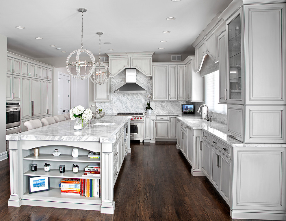Klassisk inredning av ett stort kök, med en undermonterad diskho, luckor med upphöjd panel, grå skåp, marmorbänkskiva, vitt stänkskydd, stänkskydd i sten, rostfria vitvaror, mörkt trägolv och en köksö
