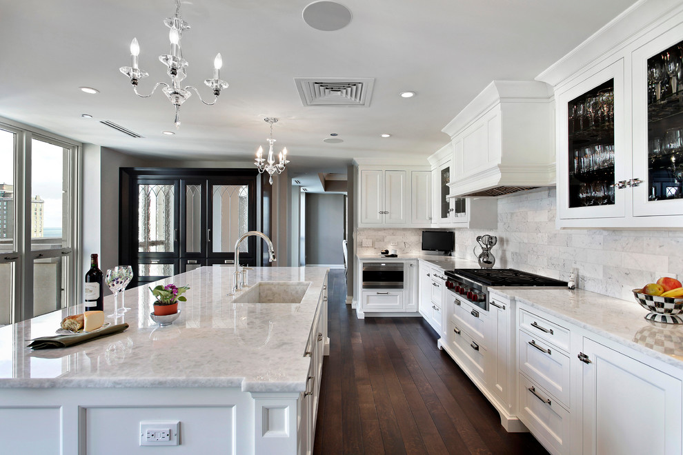 Example of a classic l-shaped eat-in kitchen design in Chicago with recessed-panel cabinets, white cabinets, marble countertops, white backsplash, paneled appliances and an island