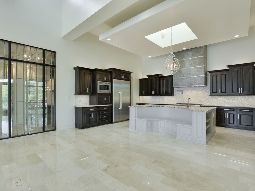 Example of a large transitional u-shaped porcelain tile, beige floor and vaulted ceiling eat-in kitchen design in Austin with a farmhouse sink, raised-panel cabinets, black cabinets, granite countertops, gray backsplash, mosaic tile backsplash, stainless steel appliances, an island and white countertops