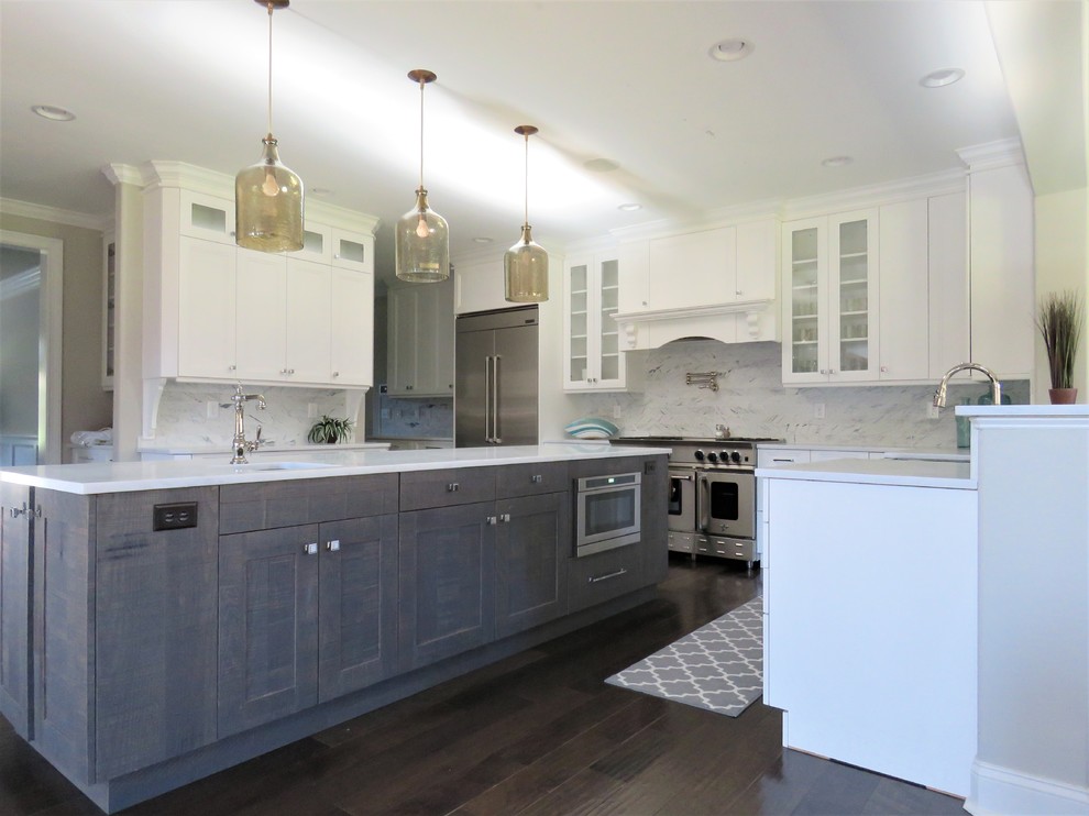 This is an example of a large classic u-shaped kitchen/diner in Philadelphia with a belfast sink, shaker cabinets, distressed cabinets, engineered stone countertops, white splashback, marble splashback, stainless steel appliances, dark hardwood flooring, an island and grey floors.