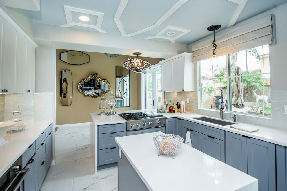 This is an example of a medium sized traditional l-shaped kitchen/diner in Los Angeles with a submerged sink, shaker cabinets, white cabinets, quartz worktops, white splashback, glass tiled splashback, stainless steel appliances, porcelain flooring, an island, white floors and white worktops.
