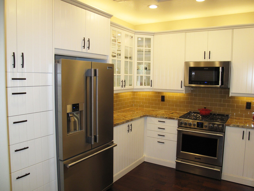 Example of a mid-sized transitional u-shaped dark wood floor enclosed kitchen design in Denver with a double-bowl sink, white cabinets, yellow backsplash, stainless steel appliances and no island