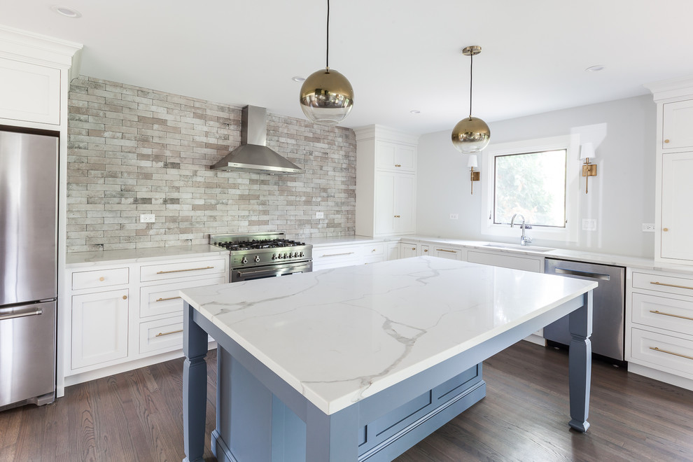 Inspiration for a large transitional u-shaped medium tone wood floor and brown floor eat-in kitchen remodel in Chicago with an undermount sink, shaker cabinets, white cabinets, quartz countertops, brown backsplash, ceramic backsplash, stainless steel appliances and an island