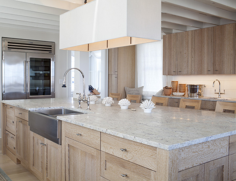 Example of a large beach style u-shaped light wood floor enclosed kitchen design in Tampa with a farmhouse sink, shaker cabinets, light wood cabinets, marble countertops, white backsplash, ceramic backsplash, stainless steel appliances and an island