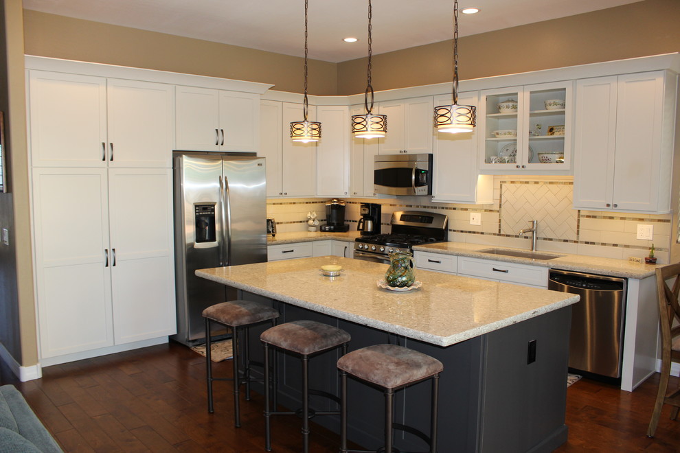 Exempel på ett mellanstort klassiskt kök, med en undermonterad diskho, skåp i shakerstil, vita skåp, granitbänkskiva, vitt stänkskydd, stänkskydd i tunnelbanekakel, rostfria vitvaror, mörkt trägolv, en köksö och brunt golv