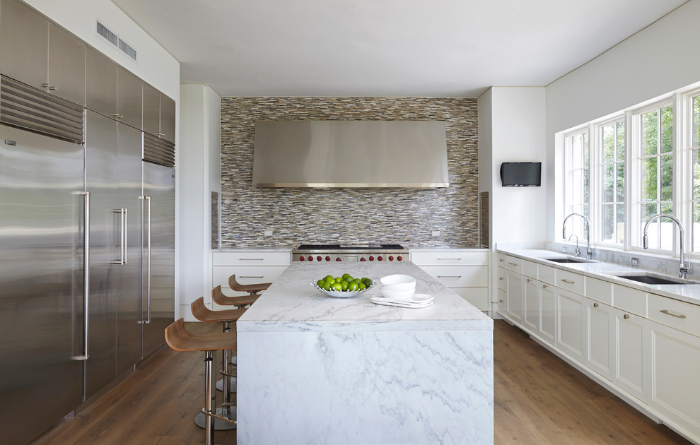 Exempel på ett klassiskt kök, med en undermonterad diskho, luckor med infälld panel, vita skåp, flerfärgad stänkskydd, stänkskydd i mosaik, rostfria vitvaror, mellanmörkt trägolv och en köksö