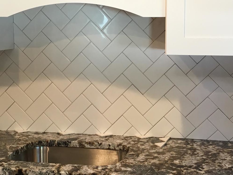 Example of a mid-sized transitional single-wall vinyl floor eat-in kitchen design in New York with an undermount sink, shaker cabinets, white cabinets, granite countertops, white backsplash, subway tile backsplash, white appliances and an island