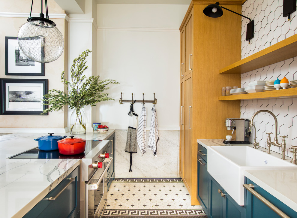 This is an example of a traditional galley kitchen in Los Angeles with a belfast sink, shaker cabinets, blue cabinets, white splashback, stainless steel appliances, a breakfast bar, multi-coloured floors and white worktops.