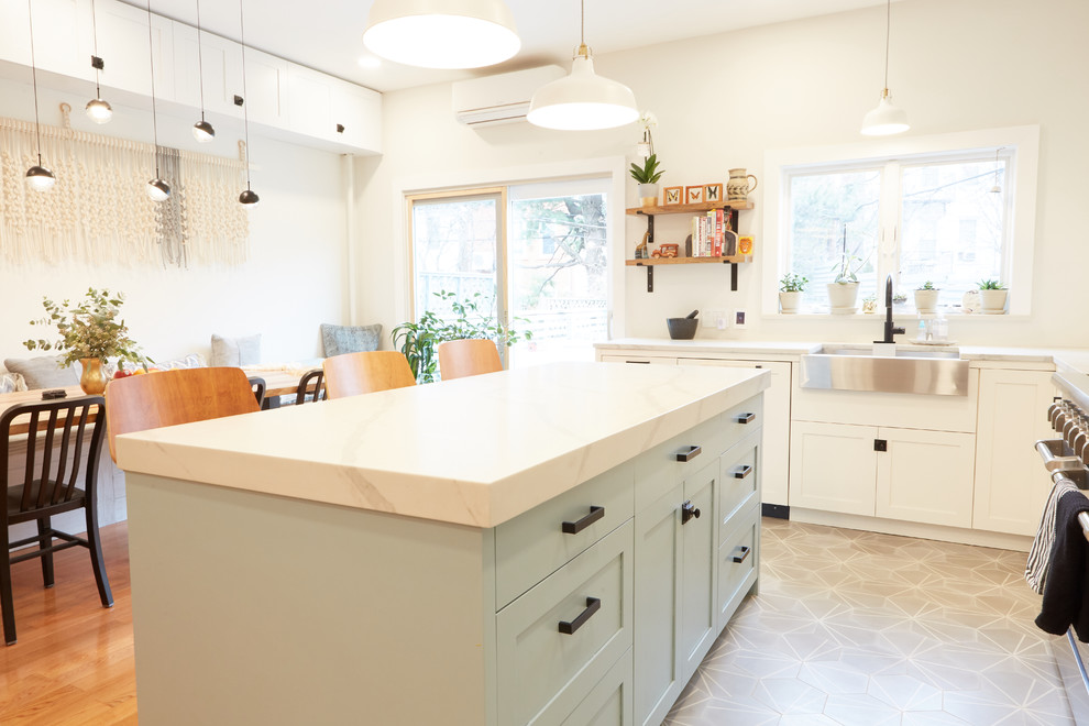 Example of a mid-sized transitional u-shaped medium tone wood floor and multicolored floor eat-in kitchen design in New York with a farmhouse sink, recessed-panel cabinets, white cabinets, quartzite countertops, white backsplash, ceramic backsplash, stainless steel appliances, an island and white countertops