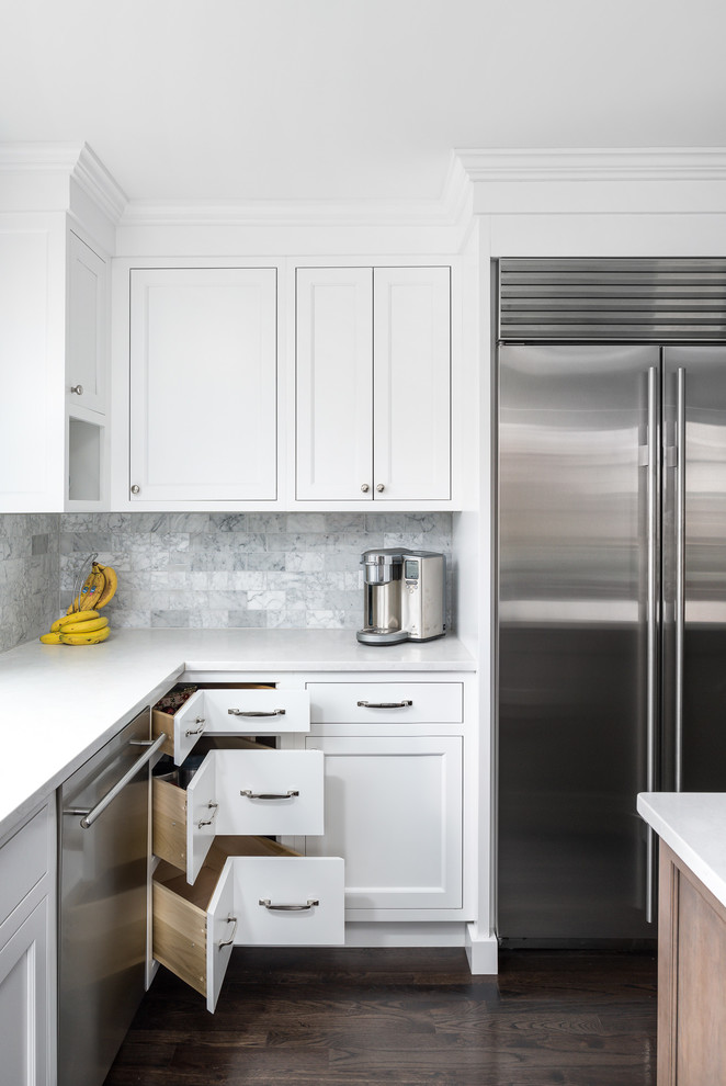 Inspiration för ett mellanstort vintage vit vitt kök, med en undermonterad diskho, vita skåp, bänkskiva i kvarts, stänkskydd i marmor, rostfria vitvaror, mörkt trägolv, brunt golv, luckor med infälld panel, grått stänkskydd och en köksö