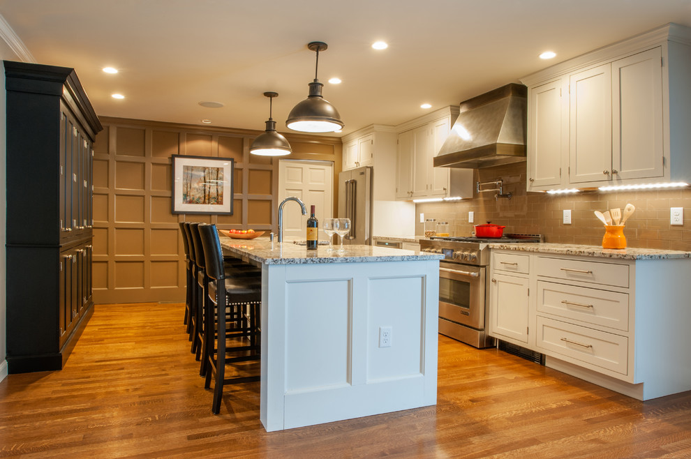 Large trendy single-wall medium tone wood floor eat-in kitchen photo in Boston with a farmhouse sink, shaker cabinets, white cabinets, granite countertops, brown backsplash, glass tile backsplash, stainless steel appliances and an island