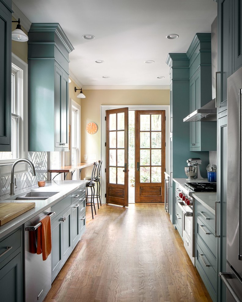 Inspiration för stora klassiska flerfärgat kök, med en undermonterad diskho, luckor med infälld panel, blå skåp, bänkskiva i kvarts, grått stänkskydd, stänkskydd i keramik, rostfria vitvaror, ljust trägolv och brunt golv