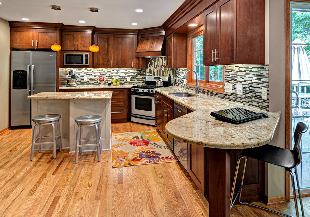 Inspiration for a transitional l-shaped open concept kitchen remodel in Minneapolis with flat-panel cabinets, dark wood cabinets, multicolored backsplash, matchstick tile backsplash, stainless steel appliances, an undermount sink and granite countertops