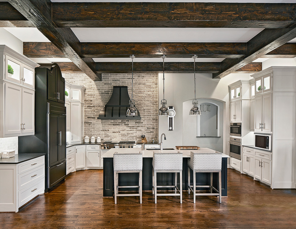 Klassische Küche in L-Form mit Unterbauwaschbecken, Schrankfronten im Shaker-Stil, Küchenrückwand in Grau, Elektrogeräten mit Frontblende, braunem Holzboden und Kücheninsel in Los Angeles