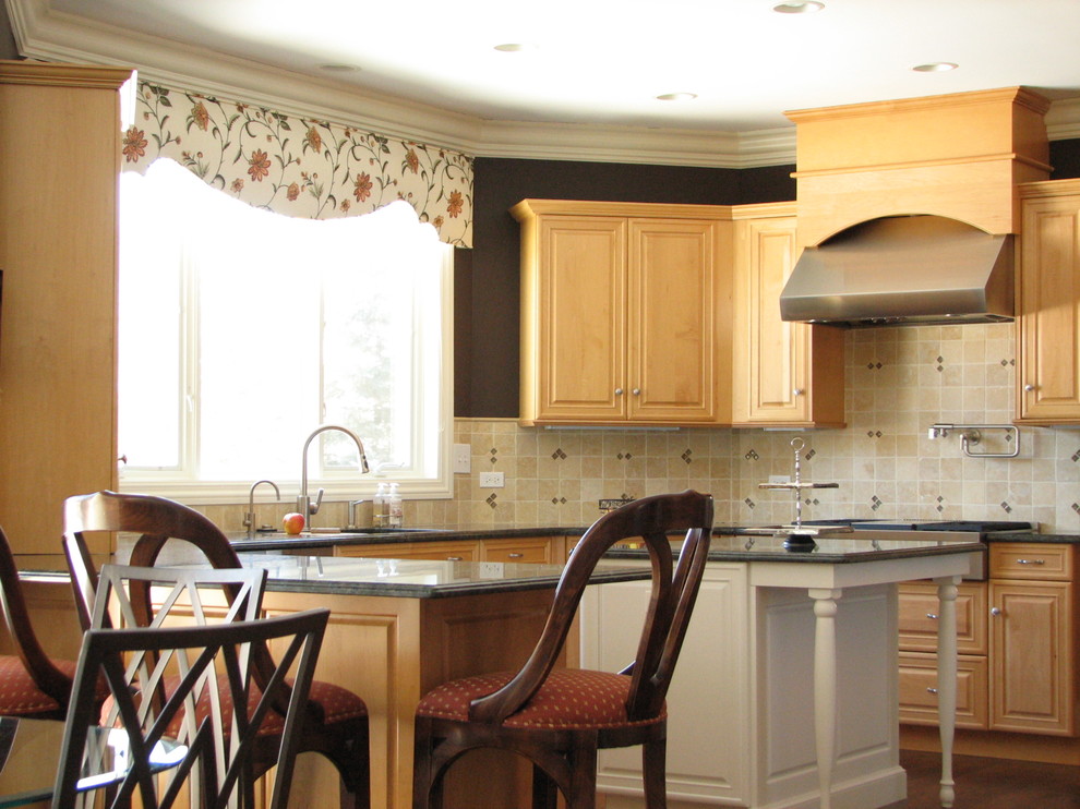 Inredning av ett klassiskt stort kök, med en dubbel diskho, luckor med upphöjd panel, skåp i ljust trä, granitbänkskiva, beige stänkskydd, stänkskydd i stenkakel, rostfria vitvaror, mörkt trägolv och en köksö