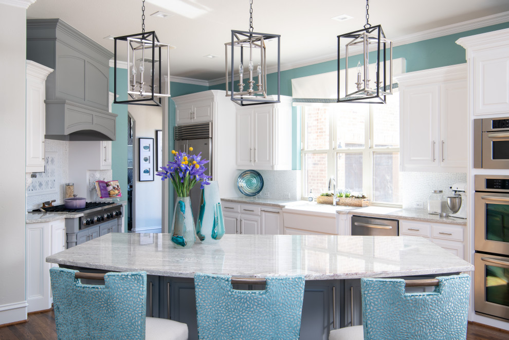 This is an example of a classic u-shaped kitchen in Dallas with a belfast sink, raised-panel cabinets, white cabinets, white splashback, stainless steel appliances, medium hardwood flooring, an island, brown floors and grey worktops.