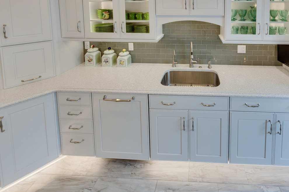 Large classic l-shaped kitchen in DC Metro with a submerged sink, raised-panel cabinets, engineered stone countertops, green splashback, metro tiled splashback and an island.