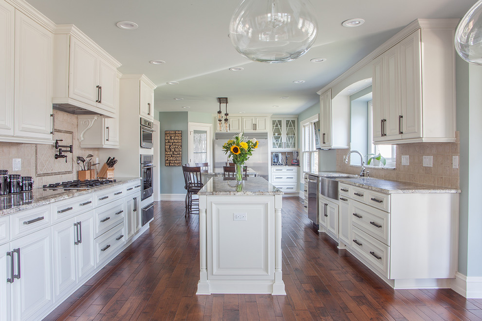 Eat-in kitchen - large transitional u-shaped dark wood floor eat-in kitchen idea in Detroit with a farmhouse sink, raised-panel cabinets, white cabinets, beige backsplash, two islands, granite countertops, ceramic backsplash and stainless steel appliances