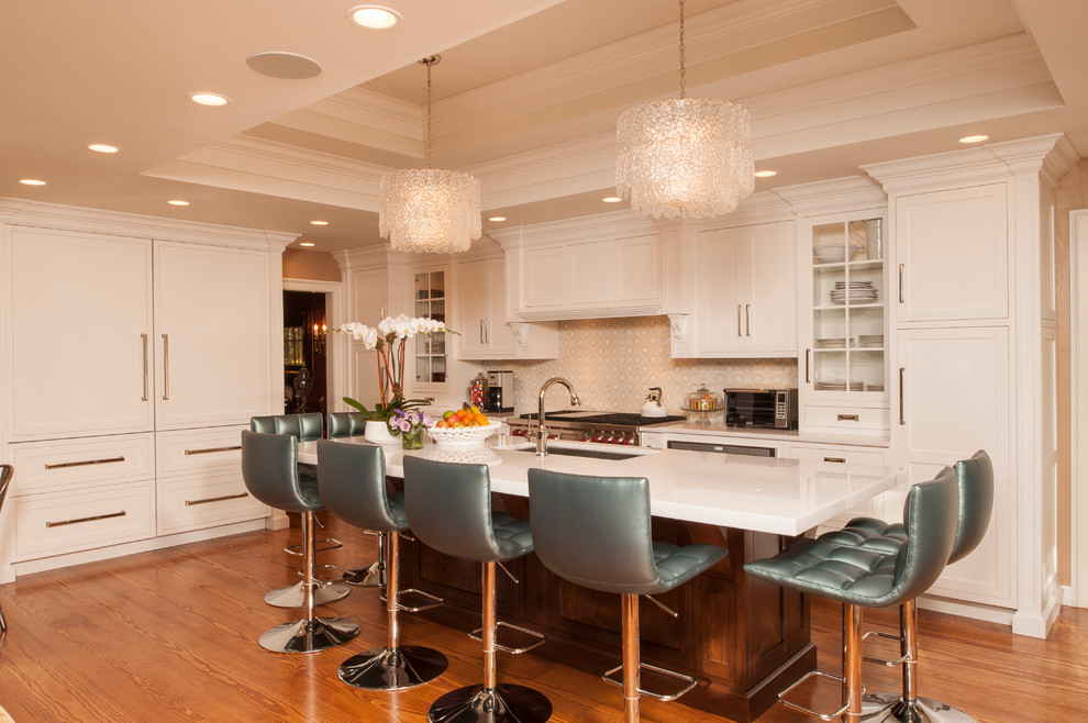 This is an example of a traditional l-shaped open plan kitchen in New York with a submerged sink, shaker cabinets, beige cabinets, composite countertops and stainless steel appliances.
