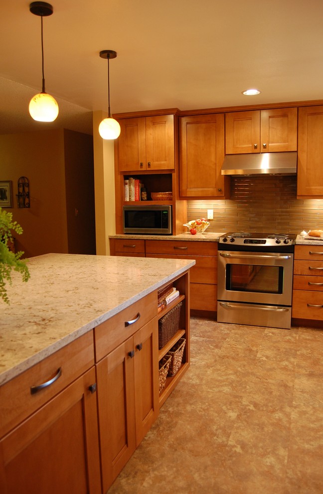 Klassisk inredning av ett litet kök, med en undermonterad diskho, skåp i shakerstil, skåp i mellenmörkt trä, bänkskiva i kvarts, brunt stänkskydd, stänkskydd i glaskakel, rostfria vitvaror och en halv köksö