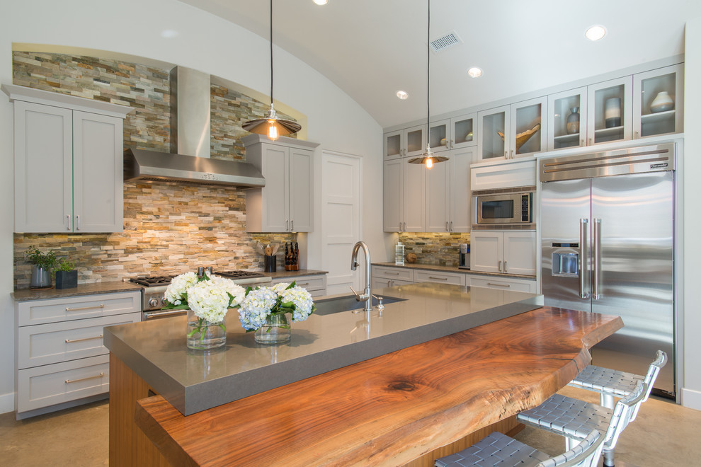 Transitional l-shaped kitchen photo in Dallas with an undermount sink, shaker cabinets, gray cabinets, wood countertops, multicolored backsplash, stone tile backsplash, stainless steel appliances and an island