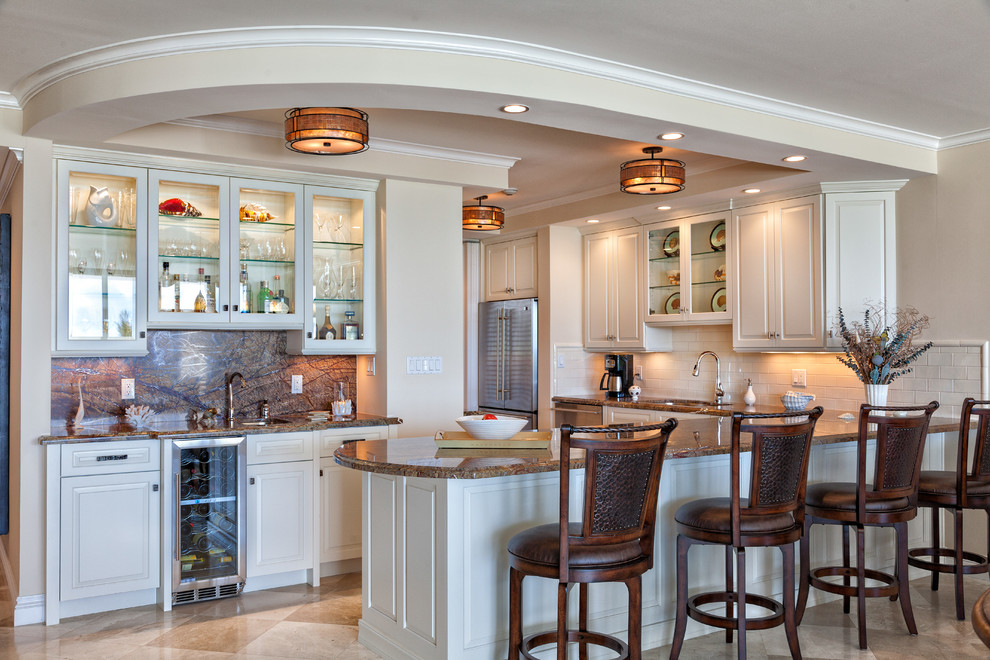Inredning av ett klassiskt kök, med en undermonterad diskho, luckor med upphöjd panel, vita skåp, vitt stänkskydd, stänkskydd i tunnelbanekakel och rostfria vitvaror